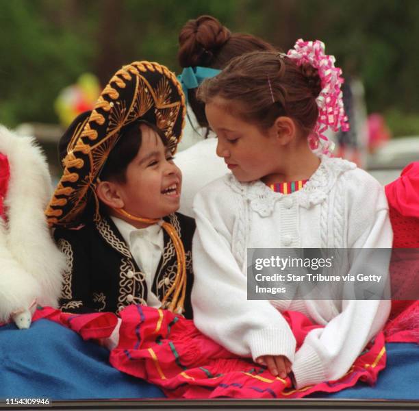 Three-year-old Kevin Centeno and seven-year-old Abby Valero, members of the Mexican folk dance group, Los Alegres Bailadores, stay warm before riding...