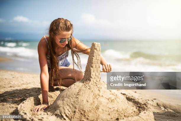 bâtiment de sandcastle de fille d’adolescente sur la plage - château de sable photos et images de collection