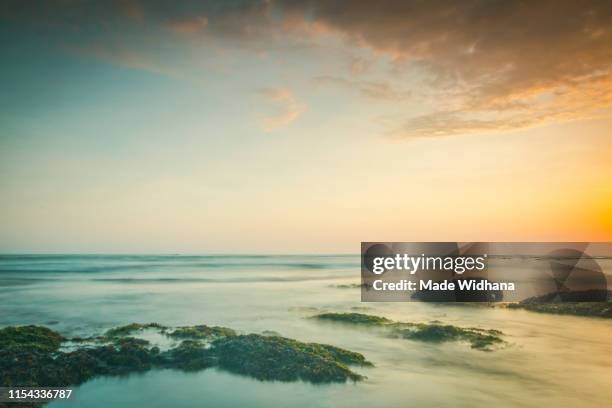 canggu beach rocks at slow sunset - made widhana stock pictures, royalty-free photos & images