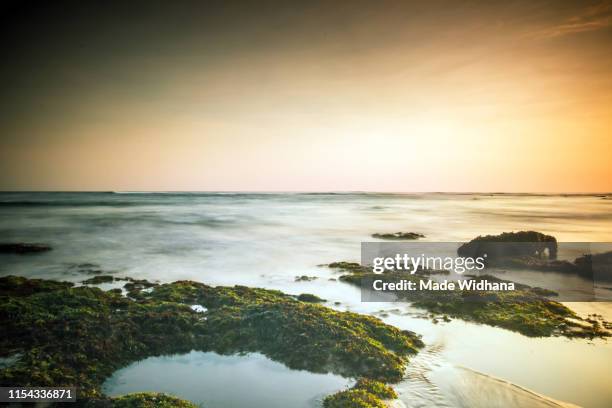 canggu beach rocks at slow sunset - made widhana stock pictures, royalty-free photos & images