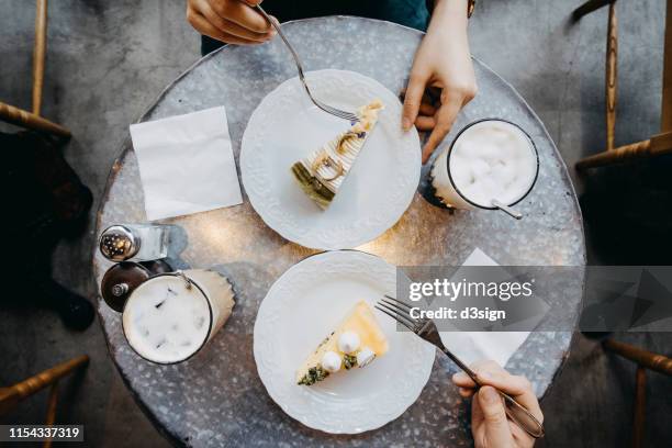 overhead view of couple having a relaxing time enjoying coffee and cream cake in cafe - chocolate cake above fotografías e imágenes de stock