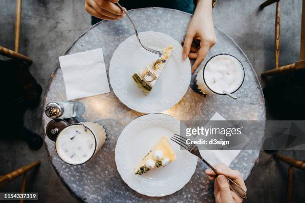 overhead view of couple having a relaxing time enjoying coffee and cream cake in cafe - cake from above stock pictures, royalty-free photos & images