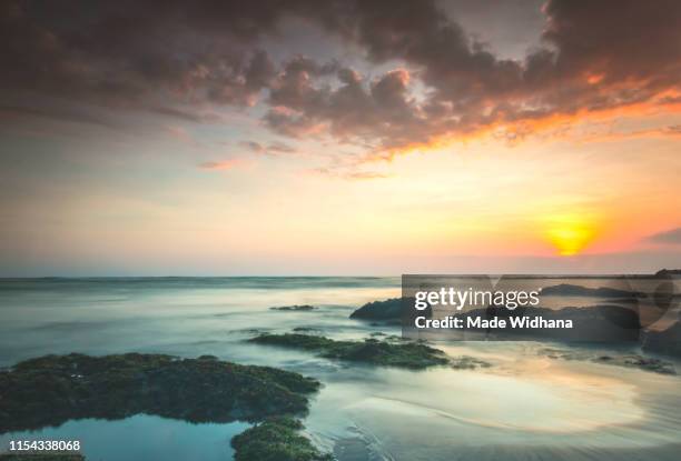 canggu beach rocks at slow sunset - made widhana stock pictures, royalty-free photos & images