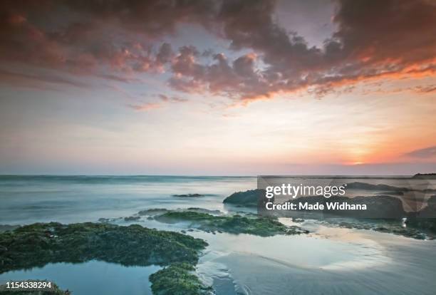 canggu beach rocks at slow sunset - made widhana stock pictures, royalty-free photos & images