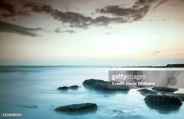 canggu beach rocks at slow sunset - made widhana stock pictures, royalty-free photos & images