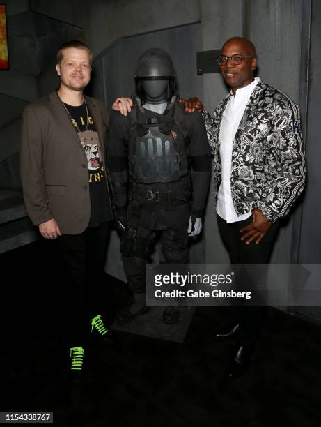 Actor Elden Henson and Welby Altidor pose next to a costume Henson wore in "The Hunger Games" movie franchise during The Hunger Games: The Exhibition...