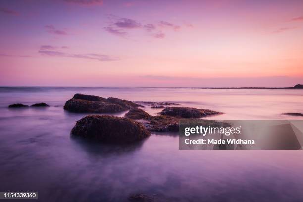 canggu beach rocks at slow sunset - made widhana stock pictures, royalty-free photos & images