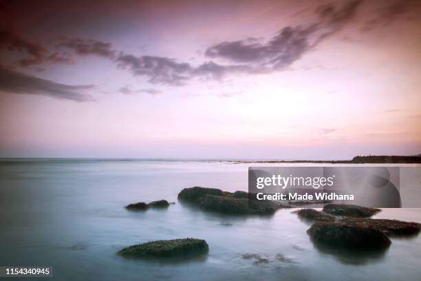 canggu beach rocks at slow sunset - made widhana stock pictures, royalty-free photos & images