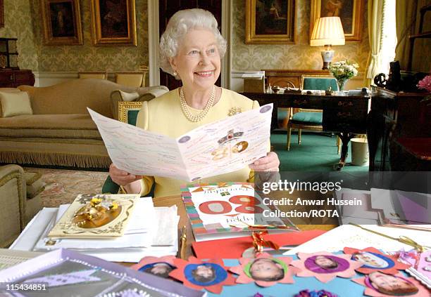 Queen Elizabeth II sits in the Regency Room at Buckingham Palace in London, April 20 as she looks at some of the cards which have been sent to her...