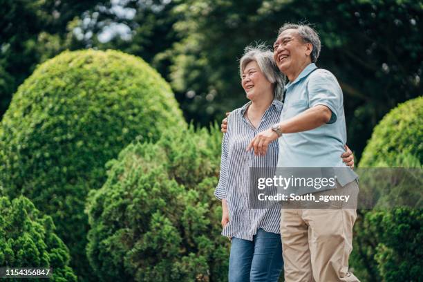 senior couple walking together in park - asian senior couple stock pictures, royalty-free photos & images