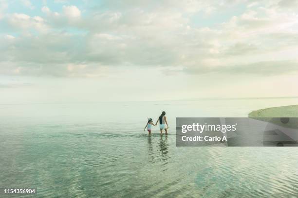 mother and daughter in water - mother and child in water at beach stock pictures, royalty-free photos & images