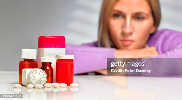 woman looking at pills - opióide imagens e fotografias de stock