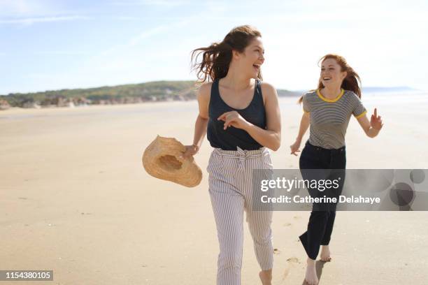 two young women enjoying on the beach - two woman running fotografías e imágenes de stock