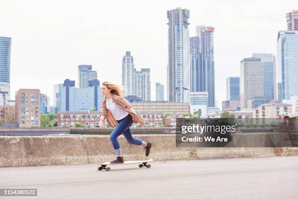 one young woman riding skateboard in city - woman longboard stock pictures, royalty-free photos & images