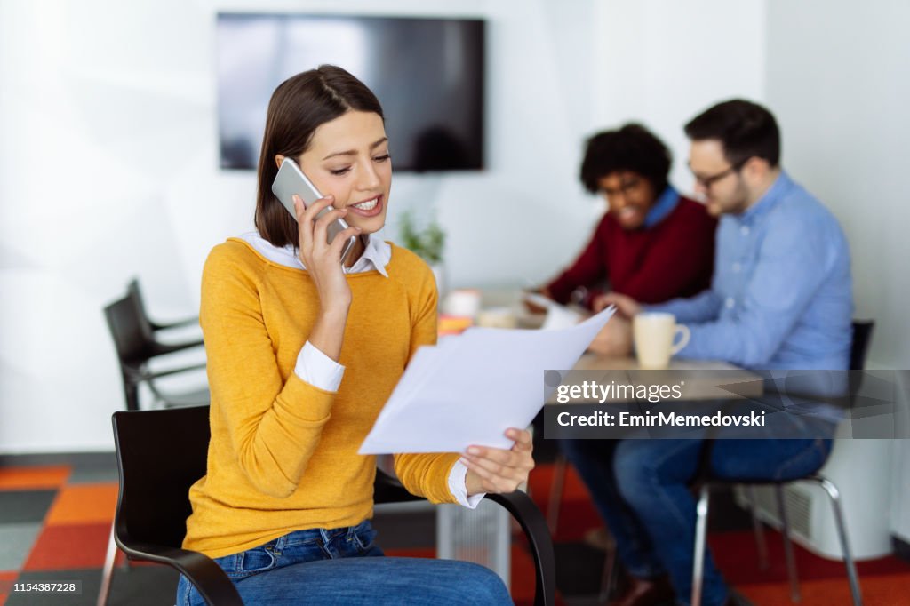 Businesswomen talking on phone while going through some paperwork