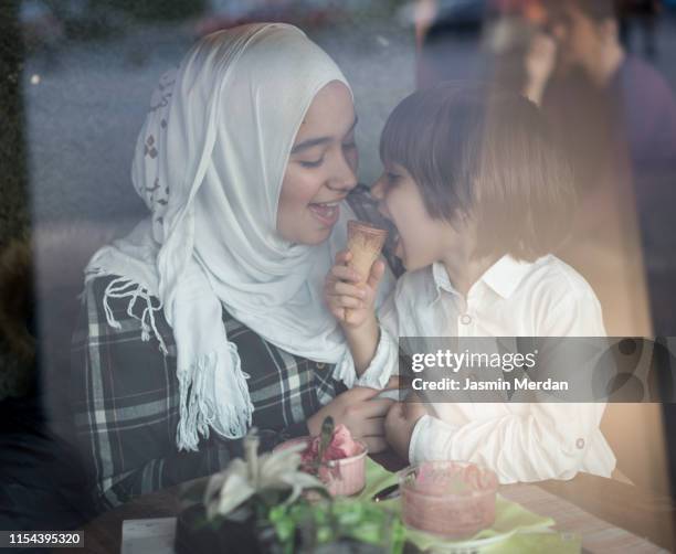 young muslim mother at restaurant with her son - halal stock pictures, royalty-free photos & images