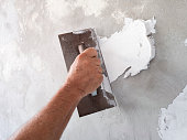 Builder using plastering tool for finishing old wall.