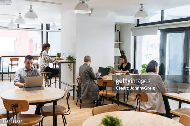 freelancers werken op computers in moderne cowerk ruimte - flexplekken stockfoto's en -beelden