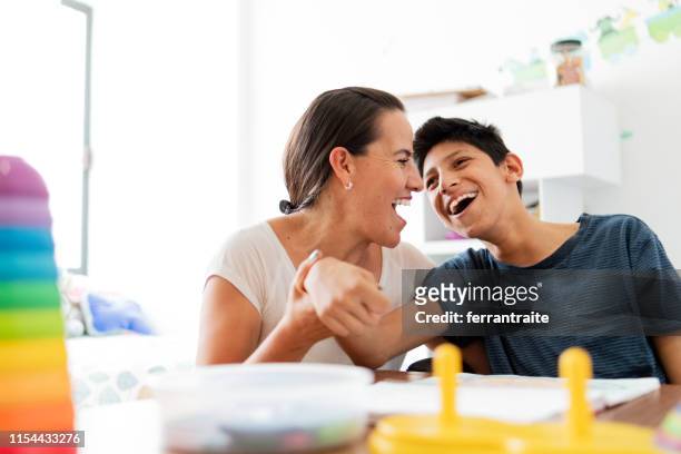 mother playing with son with cerebral palsy - physical disability stock pictures, royalty-free photos & images