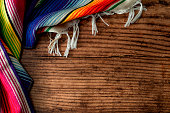 Cinco de mayo fiesta party and indigenous cultures of Mexico concept theme with a Mexican rug called a serape isolated on wood background with copyspace