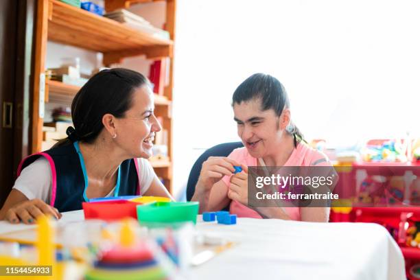 mental health professional playing with down syndrome woman - learning difficulty stock pictures, royalty-free photos & images