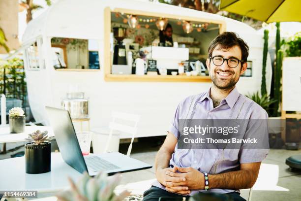 Portrait of smiling businessman working on laptop at outdoor coffee shop