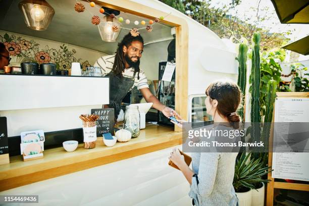smiling food truck owner taking credit card for payment from customer - foodtruck stockfoto's en -beelden