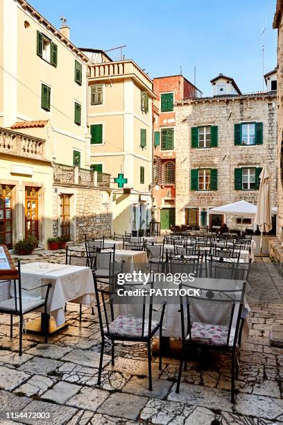 sibenik, croatia - august 23, 2017. empty tables and chairs of outdoor restaurant in old town john paul ii square - sibenik croatia stock pictures, royalty-free photos & images