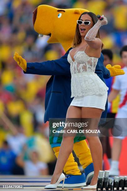 Anitta performs next to the mascot of the Copa America, Zizito, during the closing ceremony of the football tournament before the final match between...