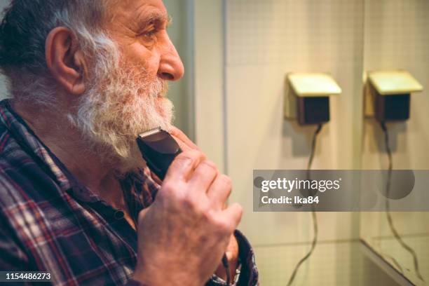 senior male starts cutting his beard off with trimmer - beard trimming stock pictures, royalty-free photos & images