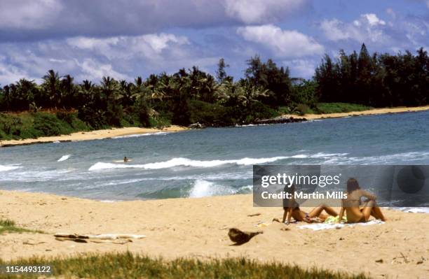 General view as two unidentified women sunbathe on the beach circa September, 1971 in Kauai, Hawaii.