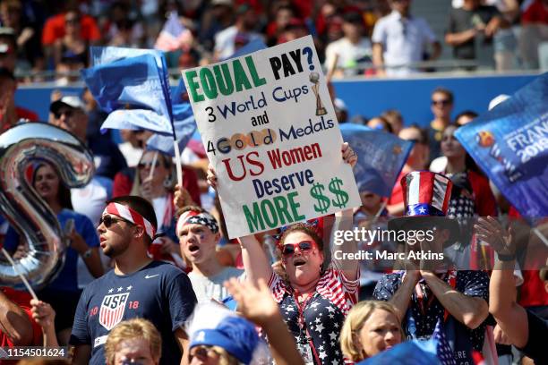 Fan holds a banner protesting the gender pay gap during the 2019 FIFA Women's World Cup France Final match between The United States of America and...