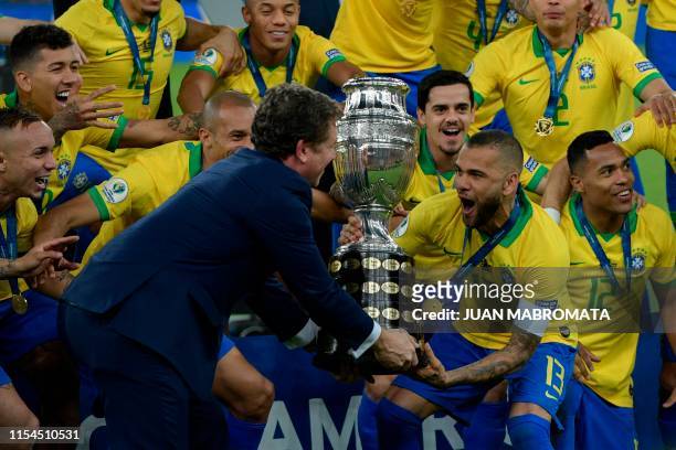 The president of the South American football's governing body Conmebol, Paraguayan Alejandro Dominguez gives the trophy to Brazil's Dani Alves after...