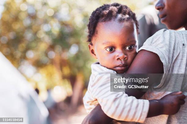 village woman carrying her baby - native african girls stock pictures, royalty-free photos & images