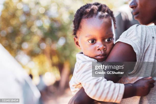 village woman carrying her baby - malnutrition children stock pictures, royalty-free photos & images