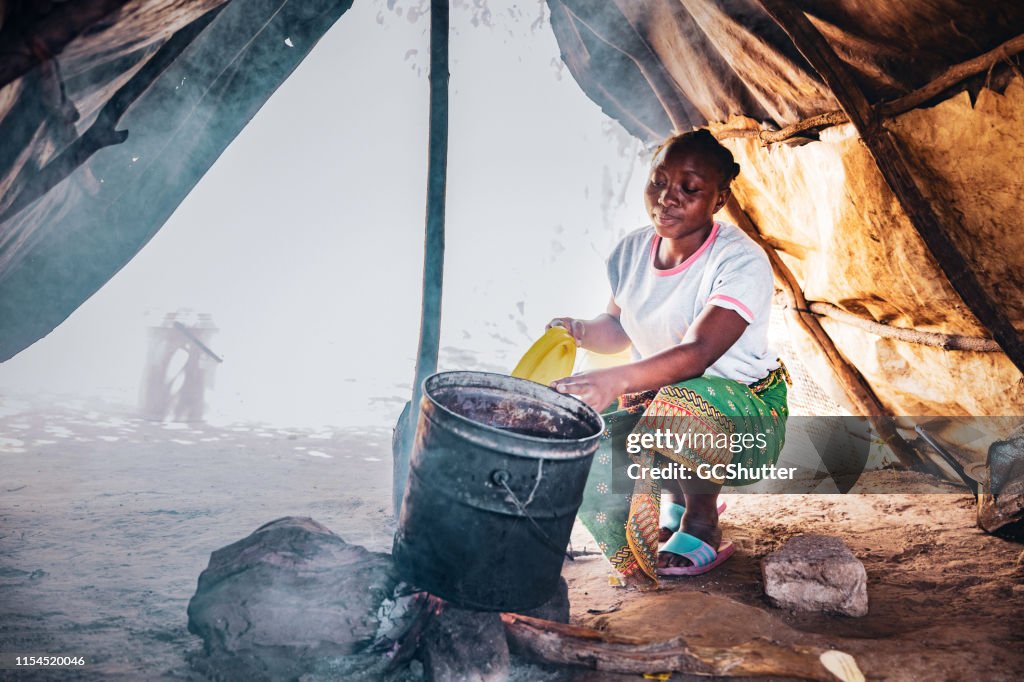 Woodfire に水を沸かしているアフリカの女性