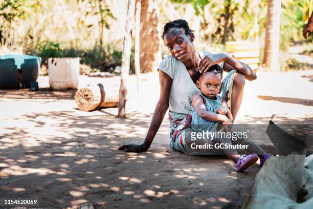 porait av en ung afrikansk kvinna sittande med sitt barn - african village bildbanksfoton och bilder