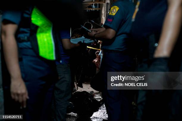 Graphic content / This photo taken on June 27 shows policemen at the crime scene where the body of a barangay health worker and former drug...