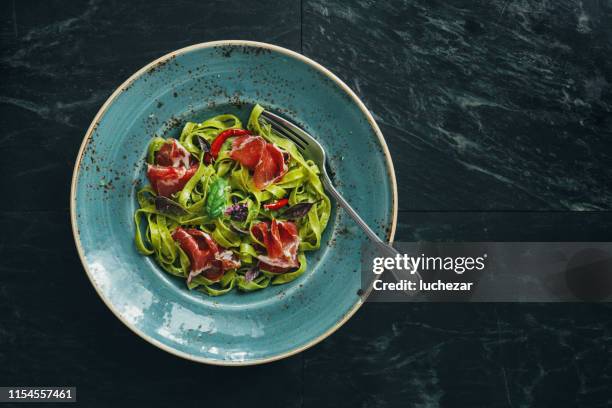 spinach pasta with basil pesto and prosciutto - prosciutto wrapped stock pictures, royalty-free photos & images