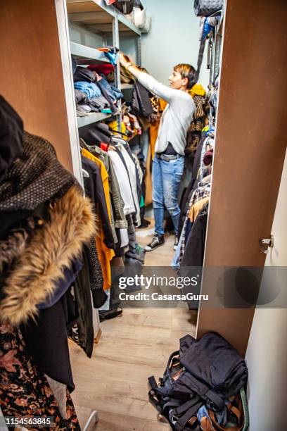 adult woman arranging the closet - overflowing closet stock pictures, royalty-free photos & images