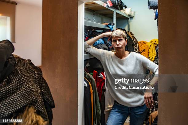 stressed woman portrait in her full messy closet - overflowing closet stock pictures, royalty-free photos & images