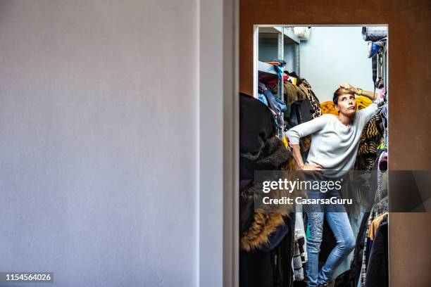 annoyed adult woman leaning on a shelf in her closet - housecleaning only women stock pictures, royalty-free photos & images