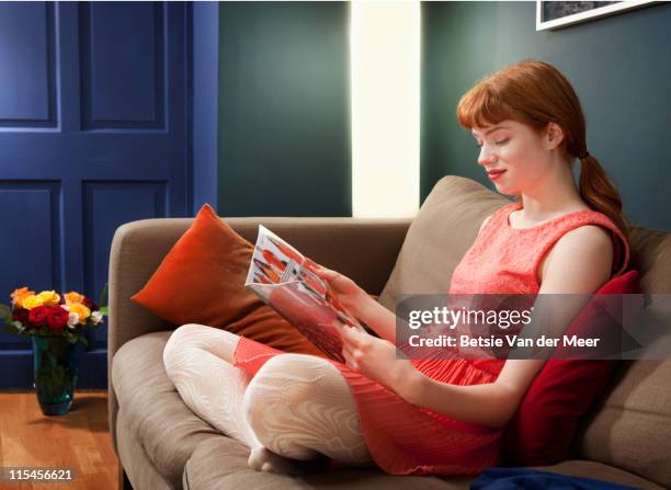 woman reading magazine, sitting on sofa. - woman reading magazine stock pictures, royalty-free photos & images