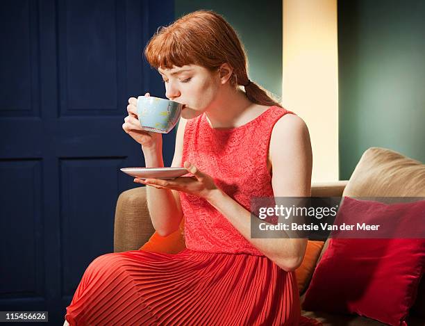 woman drinking cup of tea sitting on sofa. - taza de té fotografías e imágenes de stock