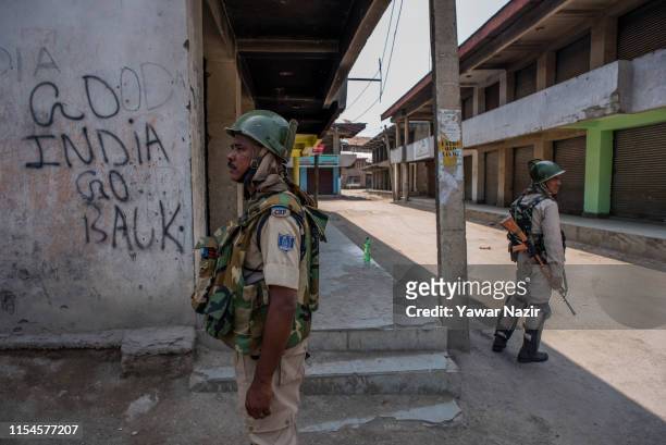 Indian paramilitary troopers stand alert in front the shuttered shops during a strike restrictions on the third death anniversary of Burhan Wani, on...