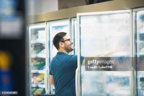 junger alleinstehender kauft lebensmittel im supermarkt - tante emma laden stock-fotos und bilder