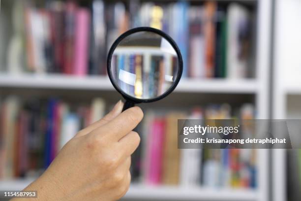 magnifying glass with books - ortografia fotografías e imágenes de stock