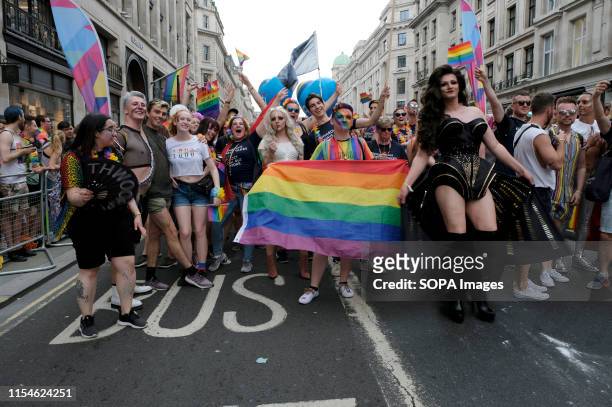 Participants pose for a photo while holding a flag during the Pride. Thousands of revellers filled Londons streets with colour to celebrate Pride in...