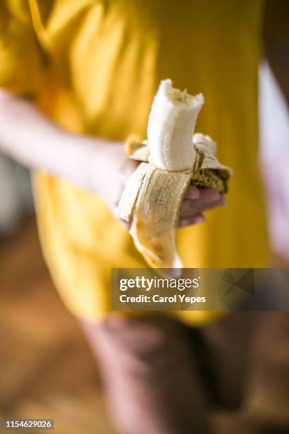 close up boy hand holding a banana ready to eat - manger sur le pouce photos et images de collection