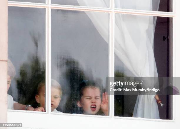 Prince George of Cambridge, Prince Louis of Cambridge and Princess Charlotte of Cambridge look out of a window of Buckingham Palace as they attend...